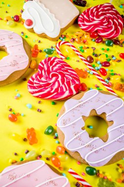 Tatlılar yaratıcı paralamak, lolipop, reçel, şeker, çerezleri çörek ve cupcakes, parlak sarı arka plana üstten görünüm kopya alanı ile tatlı kavramı