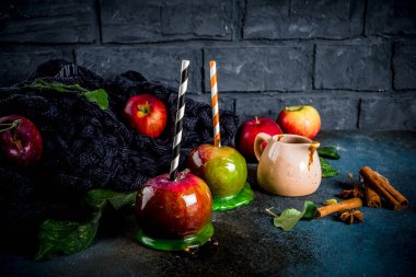 Geleneksel sonbahar incelik, karamelli elma sır. Karanlık bir arka plan üzerinde elma, yaprak, karamel sos ve sıcak bir battaniye ile. Metin için yer kopyalayın