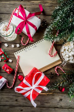 Noel kavramı, xmas tatil için hazırlık için istek listesi, santa harf not etmek. Yapılacaklar listesi için ile sıcak sıcak çikolata Kupası, Noel ağacı dekor, çam dalları. Eski ahşap masa kopya alanı üstten görünüm