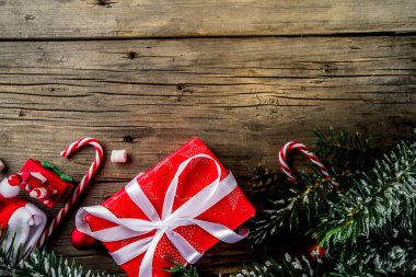 Klasik Noel arka plan, xmas ağacı süsler ve dalları, çocukların yılbaşı oyuncakları, şeker köpekler, çam kozalakları, eski ahşap masa üstten görünüm kopya alanı üzerinde santa şapka ve hediye kutuları