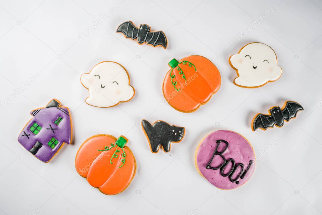 Halloween traditional children's treat, gingerbread biscuits with glaze - pumpkin, bat, black cat, ghost. On white background, top view, layout copy space