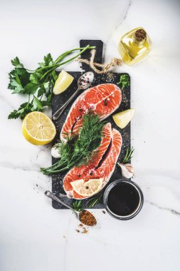 Biftek ile limon, otlar, zeytin yağı, ızgara, kayrak kesme tahtası, beyaz mermer zemin kopya alanı yukarıdaki için hazır çiğ Somon Balık