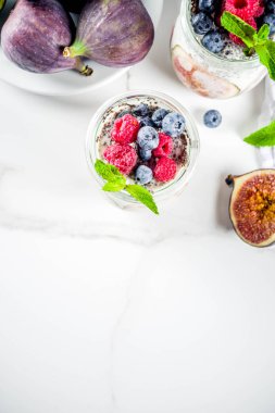 Sağlıklı detoks kahvaltı meze - yoğurt güler yüzlü veya milkshake incir, yaban mersini, ahududu chia tohumu, beyaz mermer zemin, kopya alanı ile