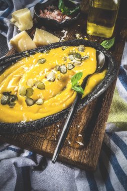 Balkabağı parmesan çorbası kabak çekirdeği, fesleğen yaprakları ve parmesan peyniri wit, mavi arka plan kopya alanı yukarıdan ışık