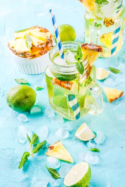 Tropical drink,  Pineapple mojito or lemonade with fresh lime and mint  light blue background, copy space