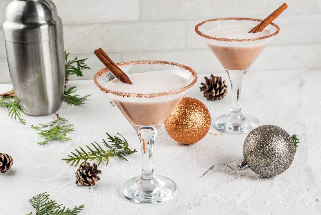 Ideas and recipes for Christmas drink. Eggnog martini, with cinnamon sticks, on white marble table with Christmas decoration, copy space