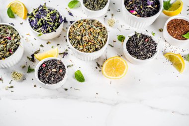 Çeşitli kuru çay - klasik siyah ve yeşil, çiçek, meyve, berry ve bitkisel çay karışımları, limon ve nane, ürün yelpazesine beyaz mermer zemin kopya alanı üst görüntüleme