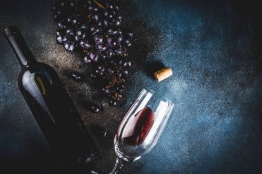 Cam ve üzüm ile kırmızı şarap şişesi, koyu arka plan kopya alanı üstten görünüm seçici odak