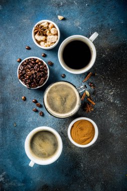 Üç kahve fincanı, fasulye, kahve ve kahverengi şeker zemin. Koyu mavi arka plan üstten görünüm alanı, metniniz için