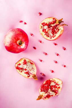 Taze çiğ sulu bütün ve kırık nar üzerinde pembe bir arka plan, üstten görünüm flatlay yaratıcı düzeni