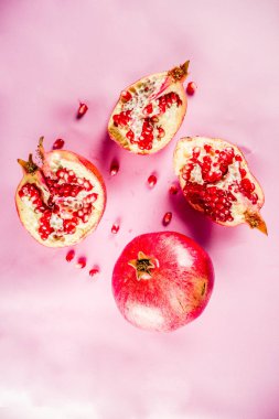 Taze çiğ sulu bütün ve kırık nar üzerinde pembe bir arka plan, üstten görünüm flatlay yaratıcı düzeni