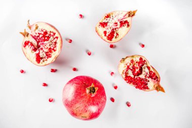 Taze çiğ sulu bütün ve kırık nar beyaz arka planda, üstten görünüm flatlay yaratıcı düzeni