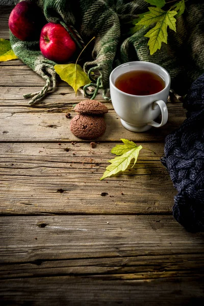 Autumn theme background, old wooden vintage planks boards, with plaid, sweater and autumn yellow leaves, tea cup, apples and chocolate chip cookies, with smartphone top view copy space