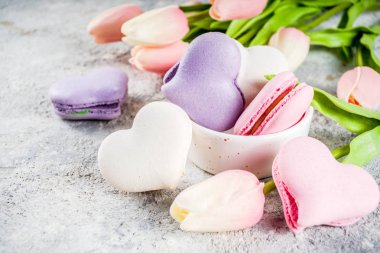 Tebrik kartı Sevgililer tatil için arka plan. Sevgililer günün sunmak, tatlı tedavi. Bir ışık gri beton zemin üzerine Lale çiçek ile ev yapımı pastel renkli macaron tanımlama alanı Kopyala