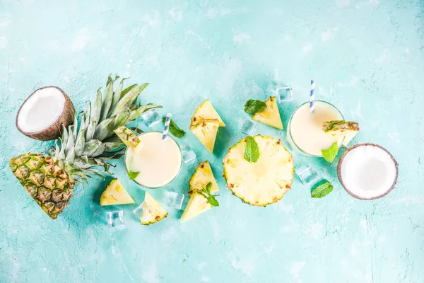 Serinletici yaz içki, kokteyl, üzerinde adet ananas, Hindistan cevizi, buz ve nane yaprakları ile bir açık mavi renkli ev yapımı pina colada alanı üst görünüm Kopyala