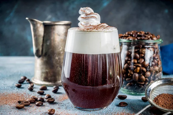 Autumn espresso drink ideas, Irish coffee cocktail with whipped cream and cocoa, blue concrete background copy space