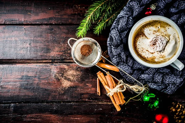 Spicy cappuccino coffee with for cold winter and autumn day. Xmas morning concept. Classic wooden background with christmas tree and decorations, copy space top view