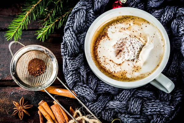 Spicy cappuccino coffee with for cold winter and autumn day. Xmas morning concept. Classic wooden background with christmas tree and decorations, copy space top view