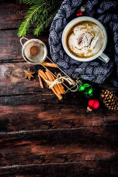 Spicy cappuccino coffee with for cold winter and autumn day. Xmas morning concept. Classic wooden background with christmas tree and decorations, copy space top view