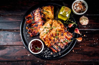 Grilled meat concept. bbq pork ribs with barbeque sauce, olive oil. fresh herbs on dark wooden background copy space clipart