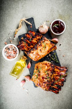 Izgara et kavramı. Barbekü domuz kaburga Barbekü sosu, zeytin yağı ile. gri taş zemin üzerine taze otlar alanı Kopyala