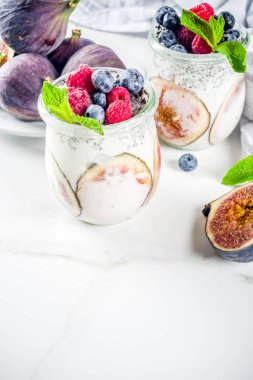 Sağlıklı detoks kahvaltı meze - yoğurt güler yüzlü veya milkshake incir, yaban mersini, ahududu chia tohumu, beyaz mermer zemin, kopya alanı ile