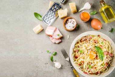 Geleneksel İtalyan Makarna, spagetti carbonara pastırma, krem sos, parmesan peyniri, yumurta sarısı ve taze fesleğen yaprakları gri taş arka plan kopya alanı