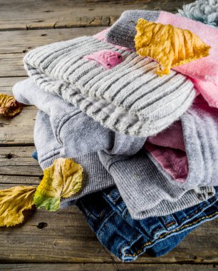 Sonbahar dizi şık giyim ve sıcak bir kız - hoodie, kot pantolon, eldiven, bir eski rustik ahşap zemin, sarı yapraklar, üstten görünüm kopya alanı ile üzerine bir ponpon şapkalı için giyim Sonbahar