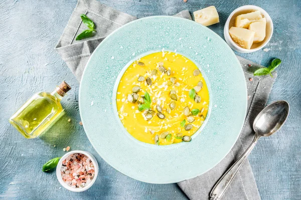 Balkabağı parmesan çorbası kabak çekirdeği, fesleğen yaprakları ve parmesan peyniri wit, mavi arka plan kopya alanı yukarıdan ışık