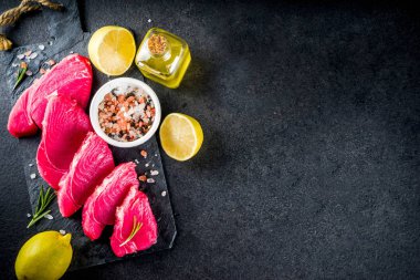 Taze çiğ ton balığı biftek yemek, malzemeler siyah taş arka plan ile uzay üstten görünüm Kopyala