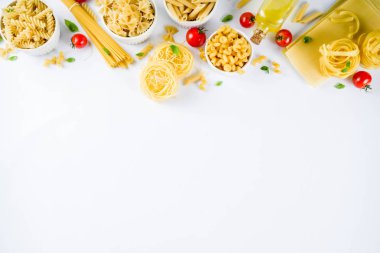 İtalyan gıda kavramı, çeşitli ham makarna çeşitler - spagetti, lazanya, düdük, tagliatelle, penne, tortellini, ravioli, domates ve fesleğen ile beyaz arka plan kopya alanı üstten görünüm bırakır