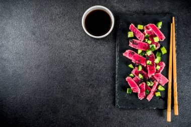 Ton balıklı sashimi poke çiğ taze balık, salatalık, siyah susam ve soya sosu, siyah taş arka plan kopya alanı