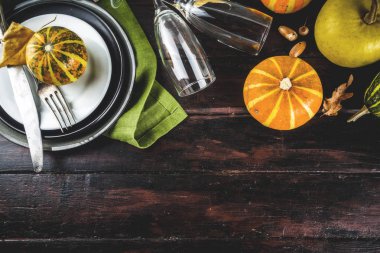 Sonbahar ve Şükran Günü kutlaması masaları. Tabaklar, çatal bıçaklar, cam ve küçük balkabaklarıyla düz yatak. Tatil dekorasyonu, ahşap arka plan, üst manzara, kopyalama alanı.