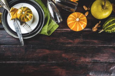 Sonbahar ve Şükran Günü kutlaması masaları. Tabaklar, çatal bıçaklar, cam ve küçük balkabaklarıyla düz yatak. Tatil dekorasyonu, ahşap arka plan, üst manzara, kopyalama alanı.