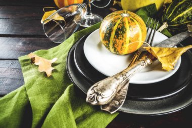 Sonbahar ve Şükran Günü kutlaması masaları. Tabaklar, çatal bıçaklar, cam ve küçük balkabaklarıyla düz yatak. Tatil dekorasyonu, ahşap arka plan, üst manzara, kopyalama alanı.