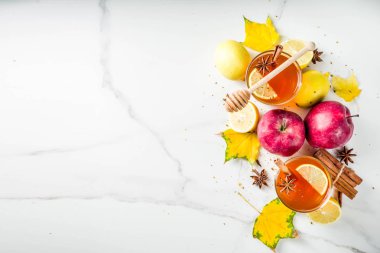 Kırmızı elma, limon, tarçın, anason, tatlım, beyaz mermer zemin ile sonbahar kış sıcak baharatlı çay iki bardak alanı Kopyala