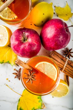 Kırmızı elma, limon, tarçın, anason, tatlım, beyaz mermer zemin ile sonbahar kış sıcak baharatlı çay iki bardak alanı Kopyala