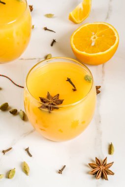 Sonbahar, kış kokteyller, sıcak ve baharatlı kış portakal, tarçın, anason yıldız, kakule, karanfil ile yumruk at. Beyaz mermer masada malzemelerle gözlük. Kopya alanı