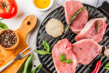 Çiğ et, domuz biftek ile baharat, otlar, zeytinyağı, beyaz mermer zemin üzerine ızgara tava, üstten görünüm alanı Kopyala