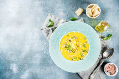 Balkabağı parmesan çorbası kabak çekirdeği, fesleğen yaprakları ve parmesan peyniri wit, mavi arka plan kopya alanı yukarıdan ışık