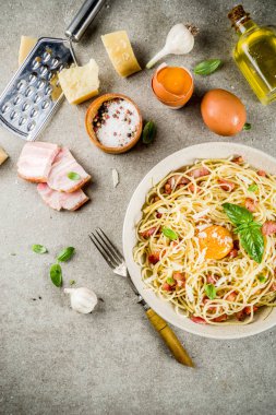 Geleneksel İtalyan Makarna, spagetti carbonara pastırma, krem sos, parmesan peyniri, yumurta sarısı ve taze fesleğen yaprakları gri taş arka plan kopya alanı