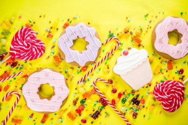 Tatlılar yaratıcı paralamak, lolipop, reçel, şeker, çerezleri çörek ve cupcakes, parlak sarı arka plana üstten görünüm kopya alanı ile tatlı kavramı