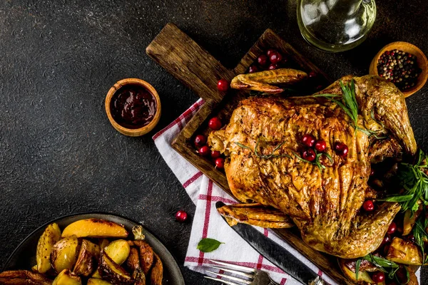 Christmas, thanksgiving food, baked roasted chicken with cranberry and herbs, served with fried vegetables and sauces on dark rusty table, copy space above