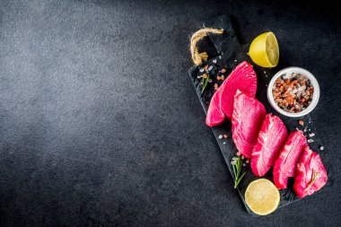 Taze çiğ ton balığı biftek yemek, malzemeler siyah taş arka plan ile uzay üstten görünüm Kopyala