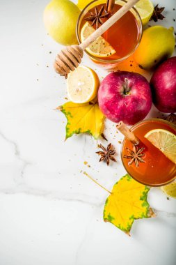 Kırmızı elma, limon, tarçın, anason, tatlım, beyaz mermer zemin ile sonbahar kış sıcak baharatlı çay iki bardak alanı Kopyala