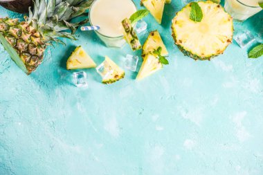 Serinletici yaz içki, kokteyl, üzerinde adet ananas, Hindistan cevizi, buz ve nane yaprakları ile bir açık mavi renkli ev yapımı pina colada alanı üst görünüm Kopyala