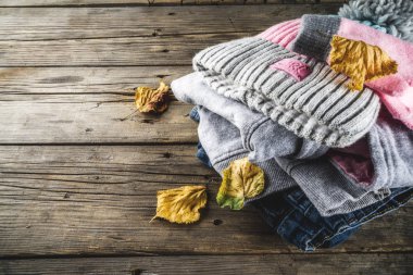 Sonbahar dizi şık giyim ve sıcak bir kız - hoodie, kot pantolon, eldiven, bir eski rustik ahşap zemin, sarı yapraklar, üstten görünüm kopya alanı ile üzerine bir ponpon şapkalı için giyim Sonbahar