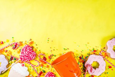 Cadılar Bayramı tatlılar kavramı, şenlikli bir kabak, şekerleme ve şeker, tanımlama bilgileri, reçel, tatlılar, parlak sarı arka plana üstten görünüm kopya alanı tam formunda kova