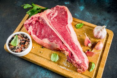 Çiğ taze et, t-bone Biftek Biftek baharat ve otlar üzerinde kesme tahtası, beton masa üstü görünümü ile kopyalama alanı