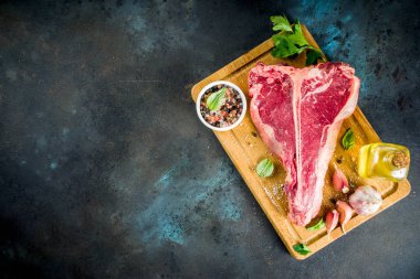 Çiğ taze et, t-bone Biftek Biftek baharat ve otlar üzerinde kesme tahtası, beton masa üstü görünümü ile kopyalama alanı